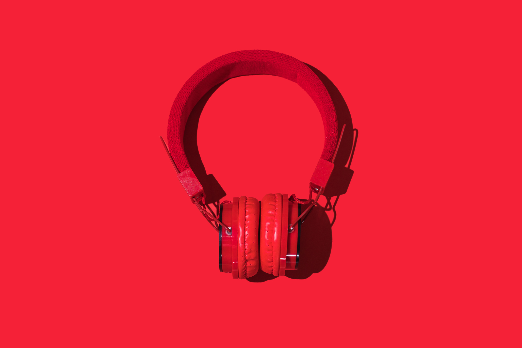 An image of a pair of wireless headphones seen in a wash of bright red light.