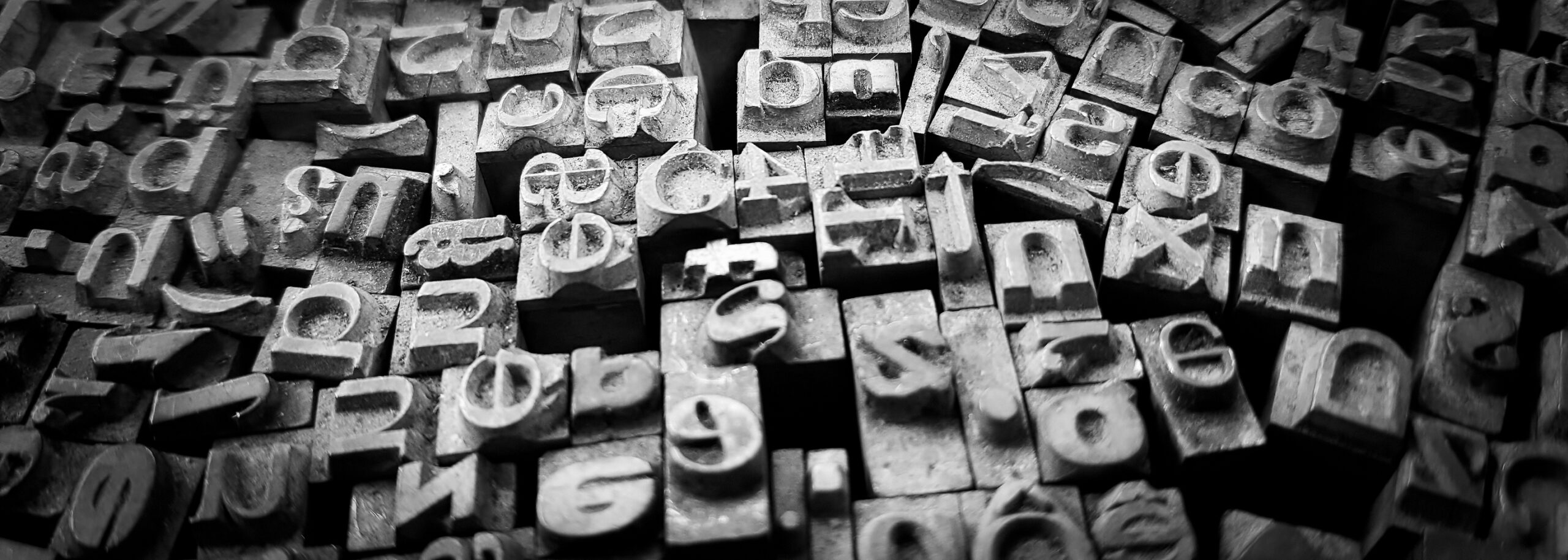 A black-and-white photo of old-time printing press metal letters scattered across a surface.